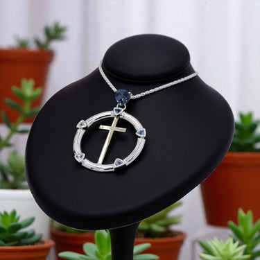 Necklace with a cross pendant on a black stand with plants in the background